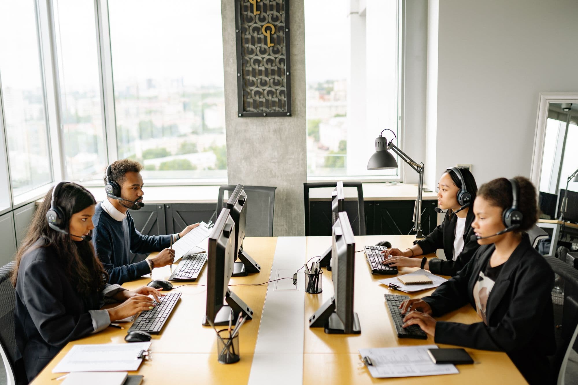 A support team in headsets working at desks beside large office windows