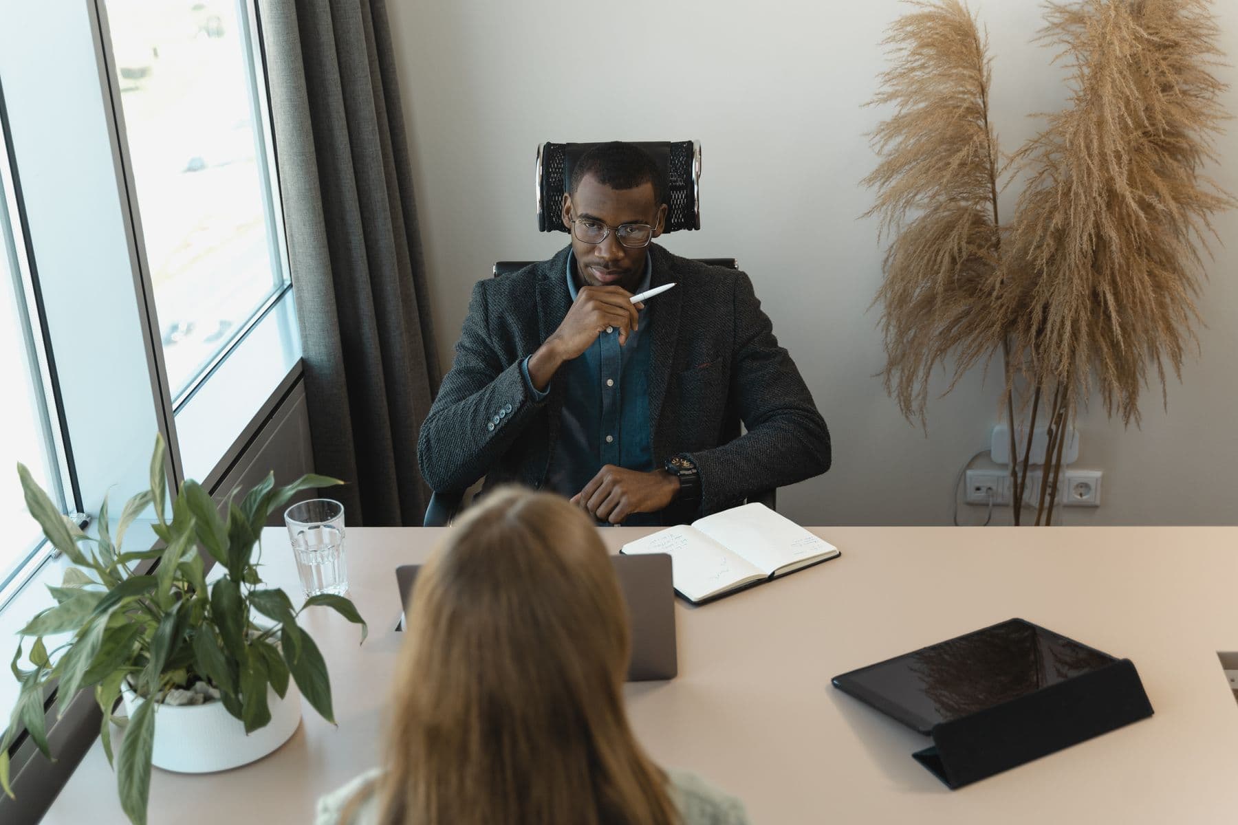An interviewer taking notes across a desk from a candidate