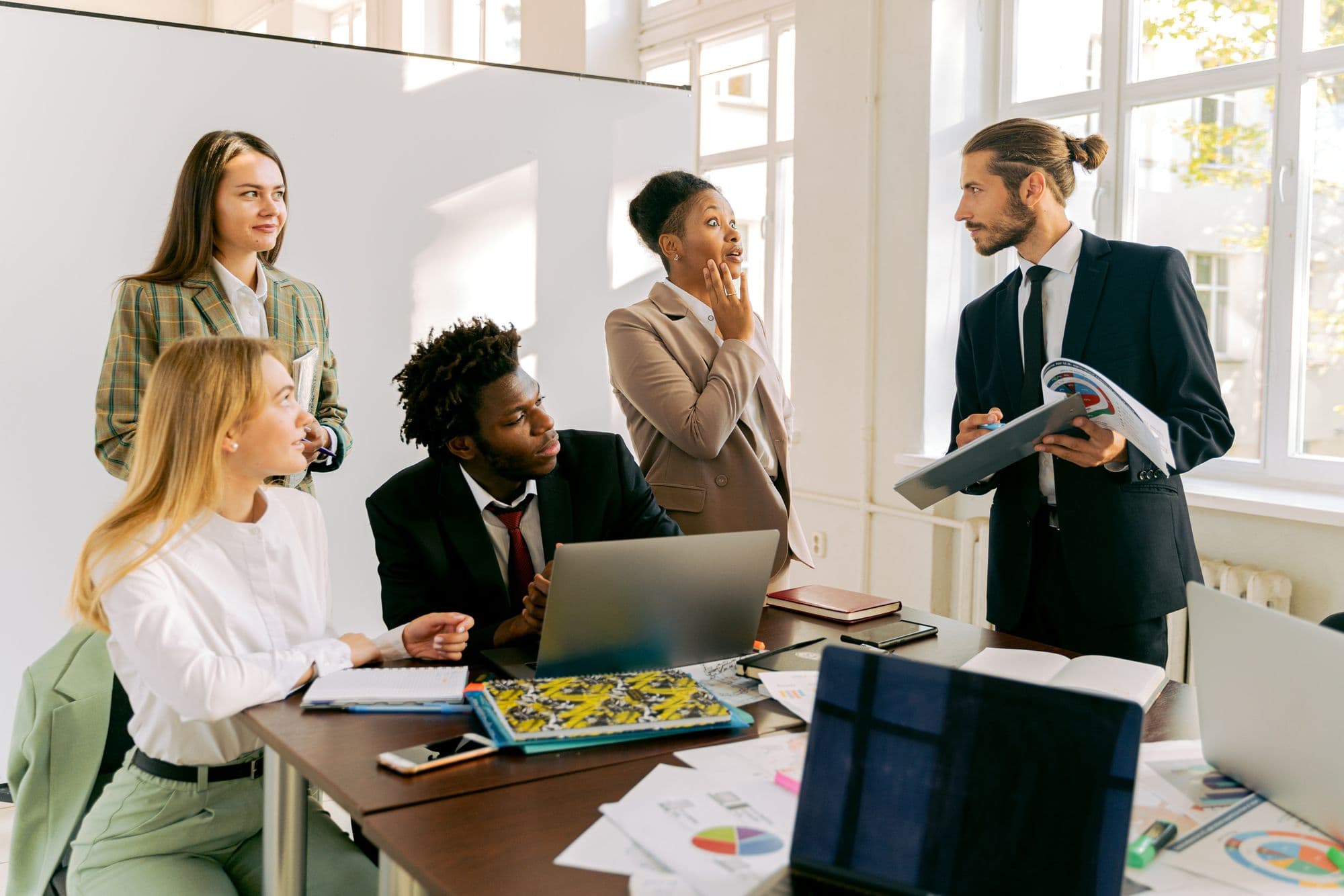 A diverse office team talking through work together around a meeting table