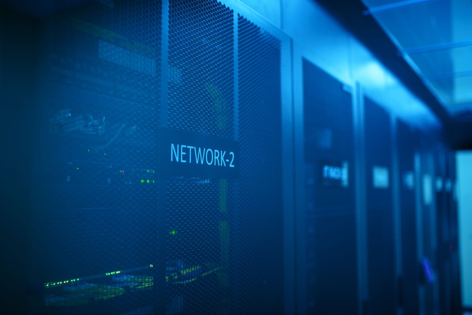 Network equipment racks lit in blue in a data centre aisle